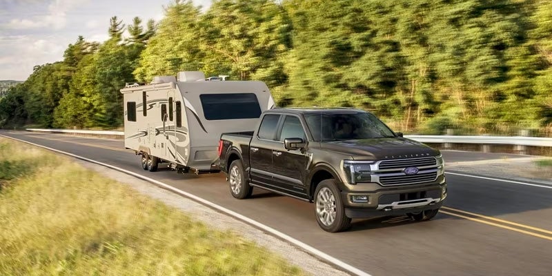 black ford f-150 running on road towing at back